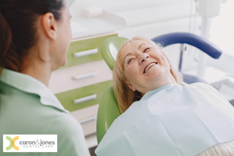 Older woman smiling on a dental chair after receiving dentures at a Kokomo dental clinic